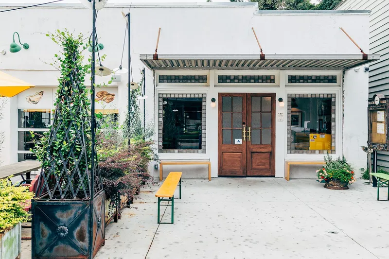 Leon's Oyster Shop Charleston storefront: white building with wooden double doors, benches and planters on the patio