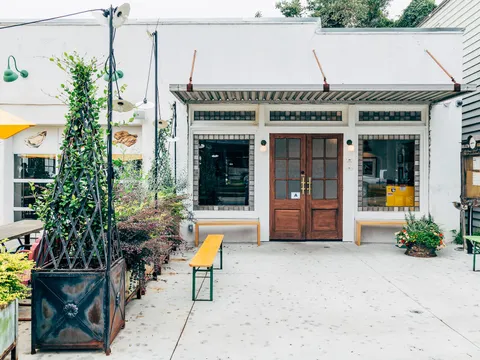 Leon's Oyster Shop Charleston storefront: white building with wooden double doors, benches and planters on the patio