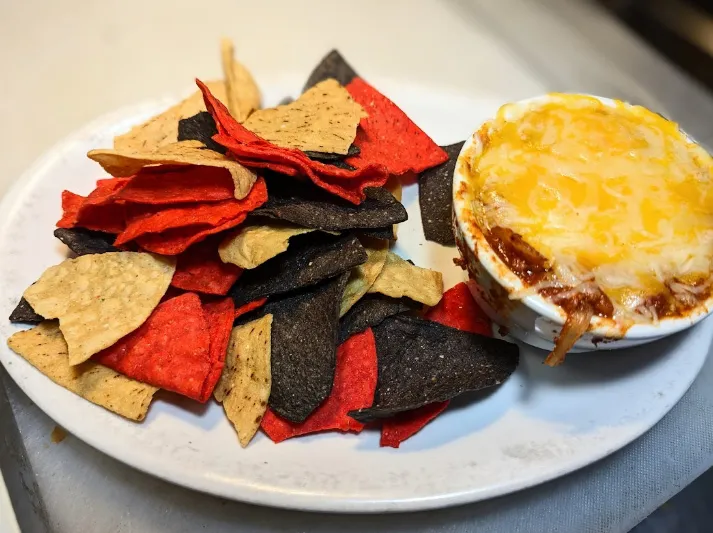 Plate of tri-colour tortilla chips with a baked dip at State Street Saloon