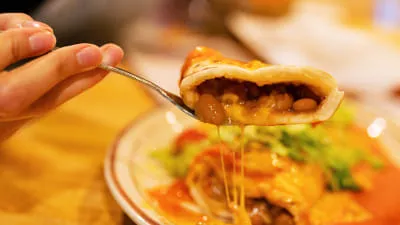 A forkful of stuffed sopaipilla with melted cheese pulled from a plate of chile-smothered New Mexican food at Duran Central Pharmacy in Albuquerque