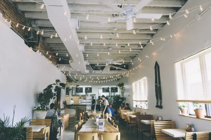 Bright dining room with wooden tables at Clavel Mezcaleria