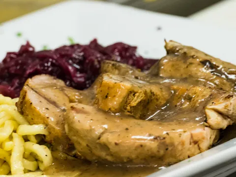 Plate of sliced German pork roast with brown gravy, buttered spaetzle, and red cabbage at Edelweiss German Restaurant in Colorado Springs