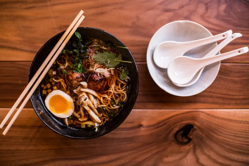 Bowl of ramen with soft egg, mushrooms and noodles beside soup spoons at Two Ten Jack, Nashville