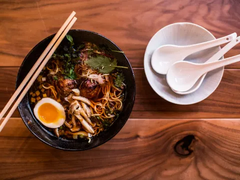 Bowl of ramen with soft egg, mushrooms and noodles beside soup spoons at Two Ten Jack, Nashville