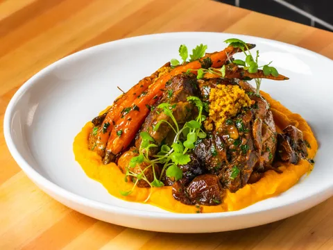 A dish with roasted carrots, mustard, and herbs at Cotton & Rye