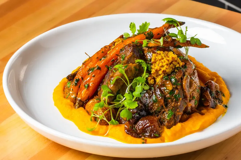 A dish with roasted carrots, mustard, and herbs at Cotton & Rye