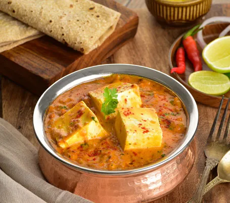 Copper serving bowl of paneer curry garnished with cilantro, served with roti, at Hyderabad House in Louisville