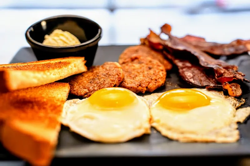 Breakfast plate of fried eggs, bacon, sausage patties and buttered toast at Quarrier Diner