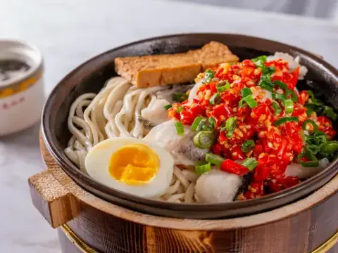 Wooden stone-pot bowl of spicy fish-fillet noodles topped with chopped red chili, scallions and a halved soft-boiled egg at Special Noodle in Las Vegas