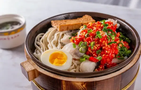 Wooden stone-pot bowl of spicy fish-fillet noodles topped with chopped red chili, scallions and a halved soft-boiled egg at Special Noodle in Las Vegas