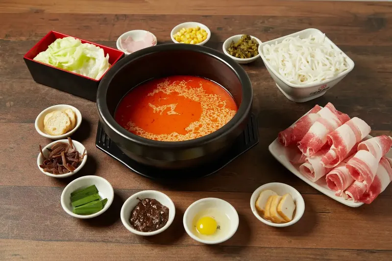 Yunnan crossing-the-bridge rice noodle set at Ten Seconds in Cary — a clay pot of chili broth surrounded by rice noodles, sliced pork, vegetables, egg and condiments