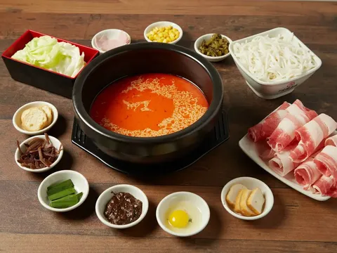 Yunnan crossing-the-bridge rice noodle set at Ten Seconds in Cary — a clay pot of chili broth surrounded by rice noodles, sliced pork, vegetables, egg and condiments