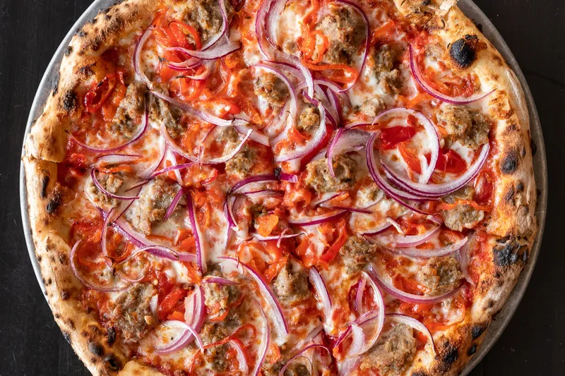 Wood-fired sausage, red onion, and pepper pizza at Pizzeria Lola in Minneapolis