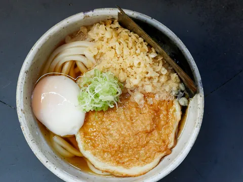 Bowl of Rintaro's hand-rolled kake/kama-tama udon topped with a soft egg, grated daikon, tenkasu and scallion, from the Rintaro website