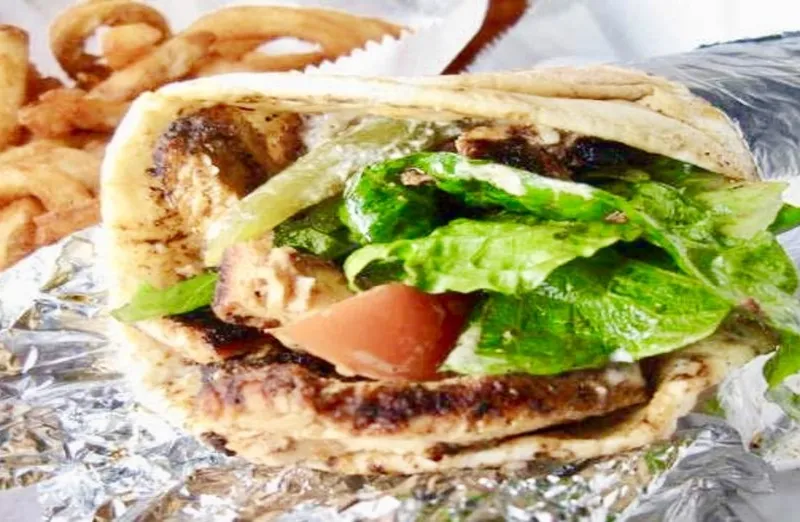Chicken shawarma wrapped in pita with lettuce and tomato, served with curly fries at Bucharest Grill in Detroit