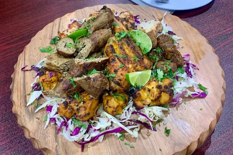 A platter of grilled kebabs, chicken, and vegetables from Tikka N Kabab.