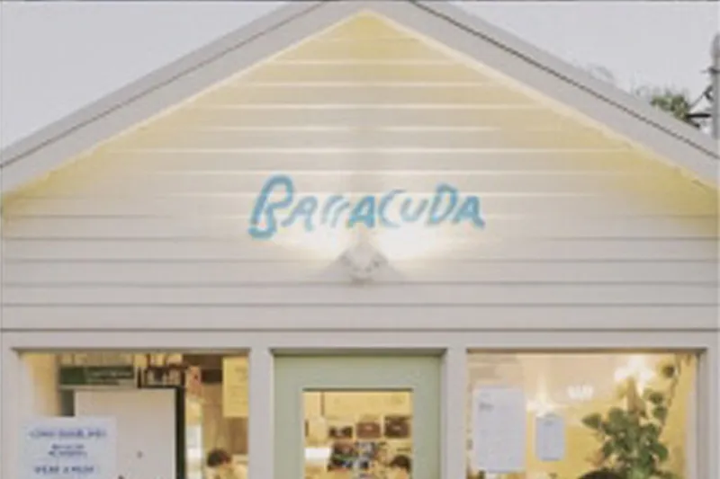 Exterior storefront of Barracuda Taco Stand at 3984 Tchoupitoulas St, New Orleans, a pale yellow gabled building with the hand-painted blue 'Barracuda' sign above the windows