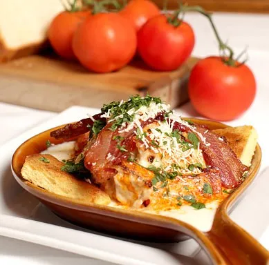 An open-faced Hot Brown sandwich topped with bacon, cheese sauce and Parmesan at The Brown Hotel