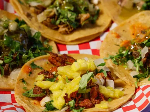 Jalisco Taqueria's al pastor and asada street tacos on corn tortillas with cilantro, onion and pineapple, served in a red-checkered paper basket