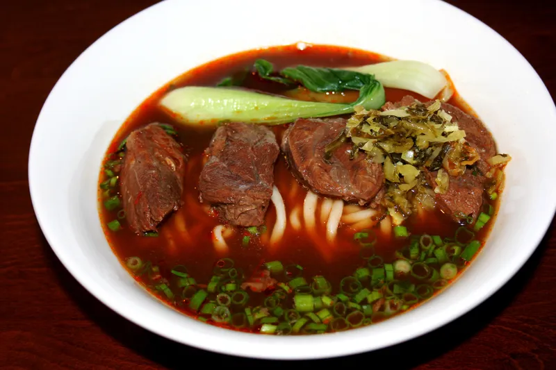 Bowl of braised beef noodle soup with bok choy, pickled mustard greens and scallions at Wu Wei Din Chinese Cuisine in Plano