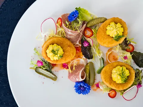 Crispy deviled eggs plated with prosciutto, cornichons and edible flowers at Lemaire in The Jefferson Hotel, Richmond