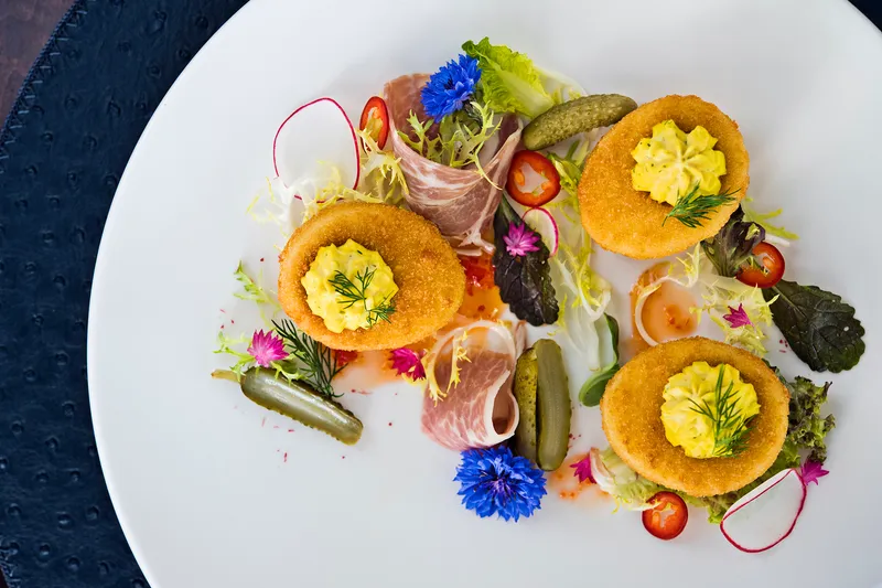 Crispy deviled eggs plated with prosciutto, cornichons and edible flowers at Lemaire in The Jefferson Hotel, Richmond