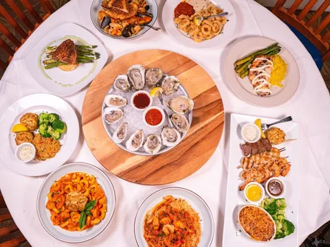 Overhead spread of oysters, seafood entrees and sides at Big Fish Grill on the Riverfront