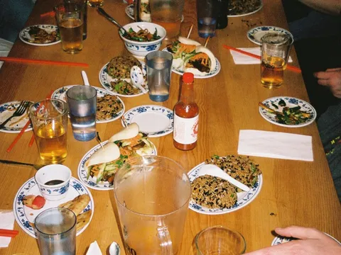 Woon dishes including noodles, fried rice, bao, chicken wings, and pickled vegetables spread across a dining table