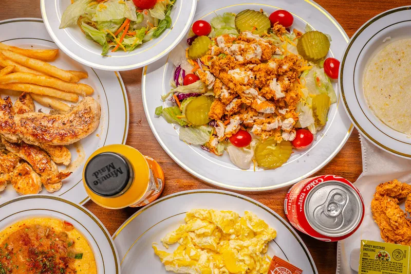 Table of Southern plates including fried chicken, catfish, eggs and grits at Sugar's Place