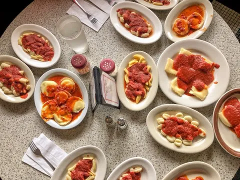 Plates of pasta with red sauce on a table at Angelo's Civita Farnese