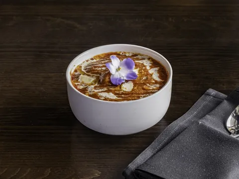 Butter chicken curry with a cream swirl and edible flower garnish, served at Artha - The Indian Bistro in Kirkland