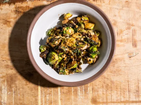 Overhead bowl of Paadee's sauteed fried brussels sprouts with egg and garlic on a wood table