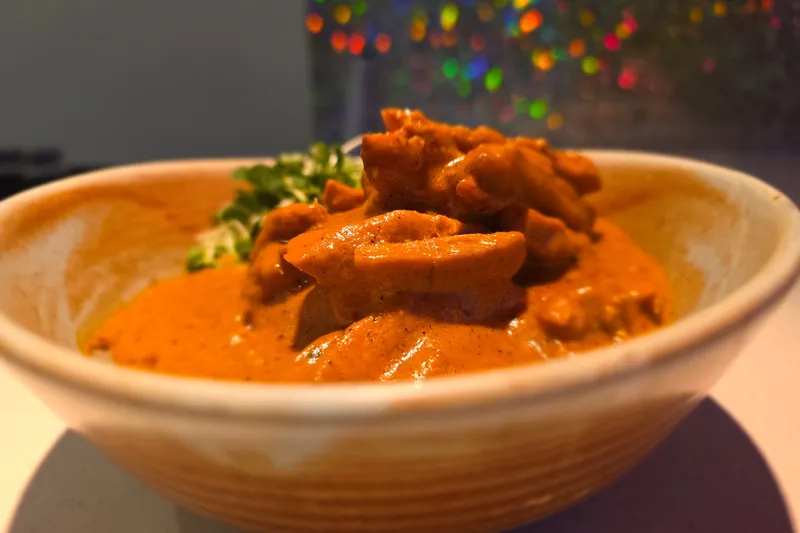 Chicken makhni (butter chicken) in a creamy tomato sauce served in a ceramic bowl at The Blue Taj