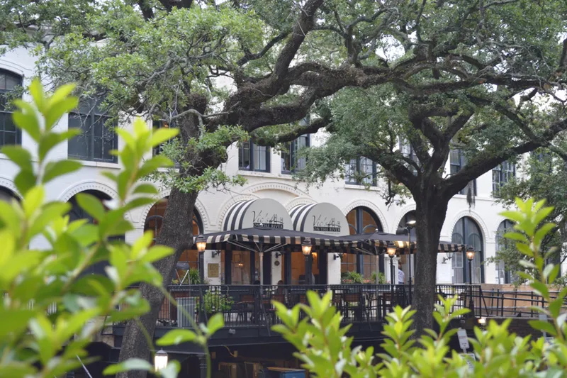 Vic's on the River in a historic Savannah cotton warehouse with black-and-white striped awnings, framed by live oaks