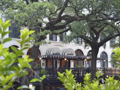 Vic's on the River in a historic Savannah cotton warehouse with black-and-white striped awnings, framed by live oaks