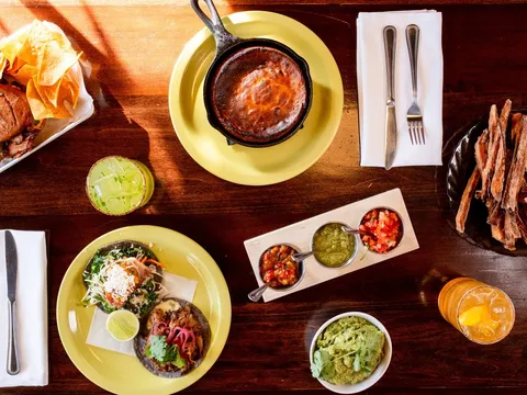 Overhead spread at Vida Cantina with a cast-iron cheese fundido, blue-corn tacos, a three-salsa flight, guacamole, sweet potato fries and margaritas