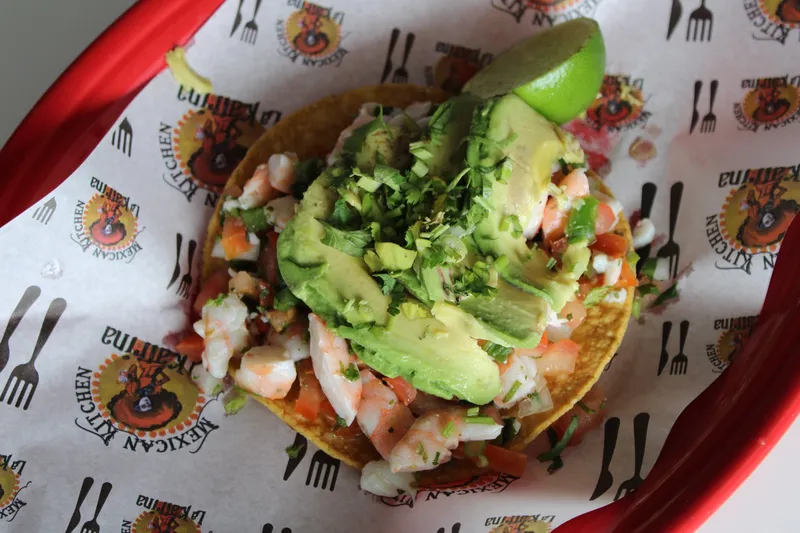 Shrimp tostada topped with fresh avocado and a lime wedge at Taqueria La Katrina