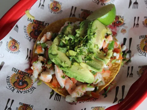 Shrimp tostada topped with fresh avocado and a lime wedge at Taqueria La Katrina