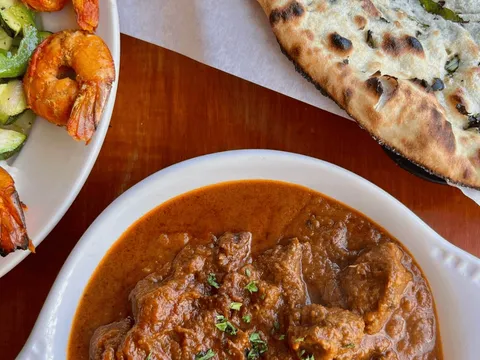 A dish of curry with a plate of tandoori shrimp, grilled vegetables and charred naan at Cedars in University District