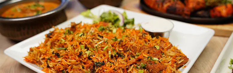 Platter of biryani with curry and tandoori chicken at Curry Corner