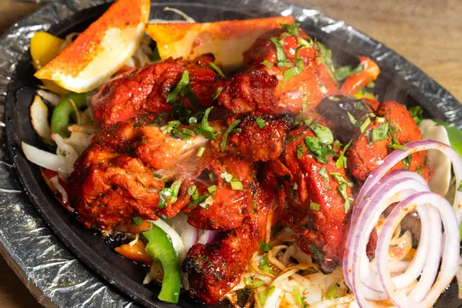 Sizzling platter of tandoori chicken with onions, peppers and lemon at Anjappar Chettinad