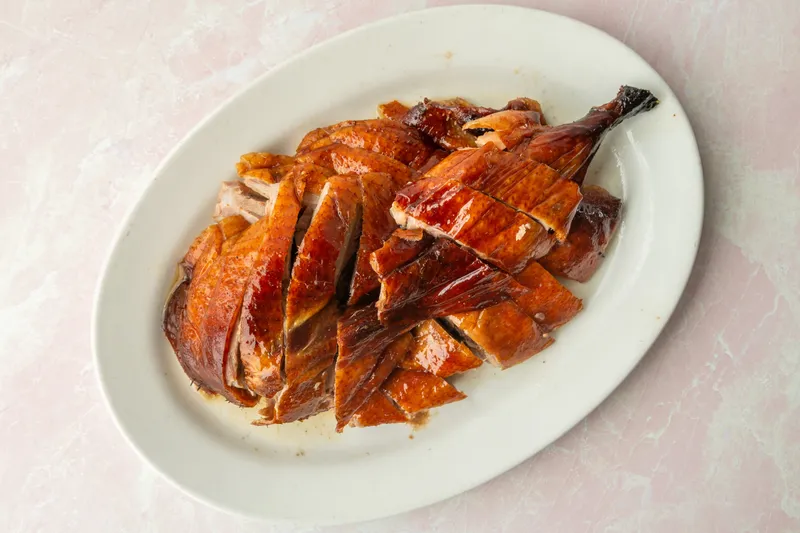 A whole Cantonese roast duck, chopped and arranged on a white oval platter at Sam Woo BBQ