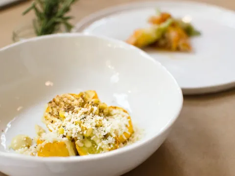 Roasted summer squash dish with grated cheese and pistachio in a white bowl at Rooster & Owl