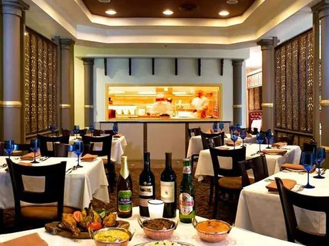 Dining room at The Indian Harvest with set tables, an open kitchen, and Indian dishes in the foreground