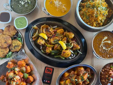Indian curries, biryani, tandoori dishes, pakoras, and chutneys arranged on a table at Curry Corner