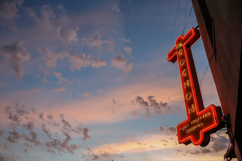Illuminated Cochon restaurant sign against the evening sky in New Orleans