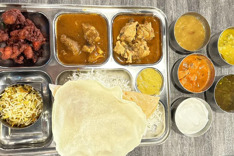 Akshaya Patra non-veg lunch thali with curries, biryani rice, papad and chutneys on a steel tray