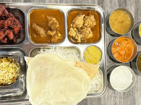 Akshaya Patra non-veg lunch thali with curries, biryani rice, papad and chutneys on a steel tray