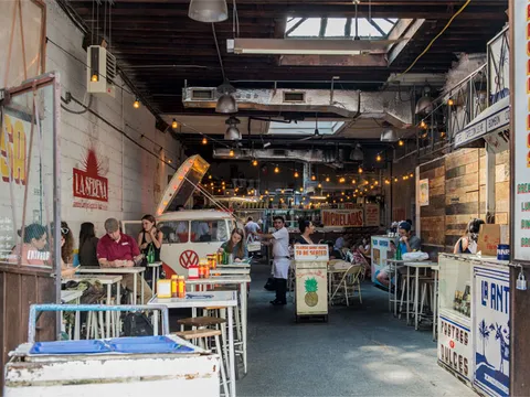 The interior of Tacombi's Nolita location, with its vintage Volkswagen van taco bar, string lights, communal tables, and hand-painted 'Bienvenidos' signage
