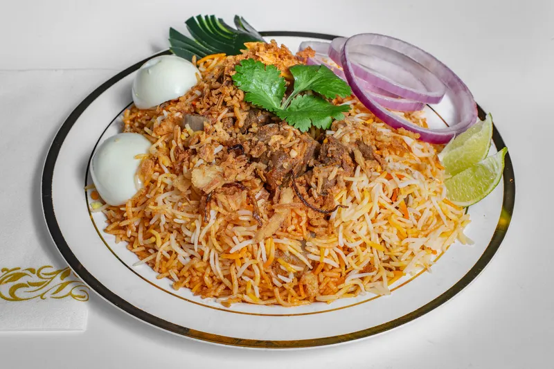 Plate of Hyderabadi mutton (goat) dum biryani with boiled egg, onion, and lime at Pastry Corner Cafe & Lounge